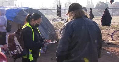 A volunteer conducts a Point-in-Time homeless count survey at a Fresno encampment