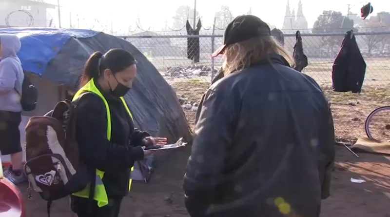 A volunteer conducts a Point-in-Time homeless count survey at a Fresno encampment